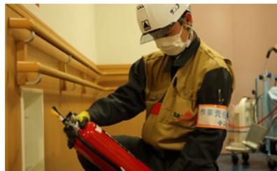 消防用設備の点検作業現場。作業員が消防設備の点検を行っている様子。